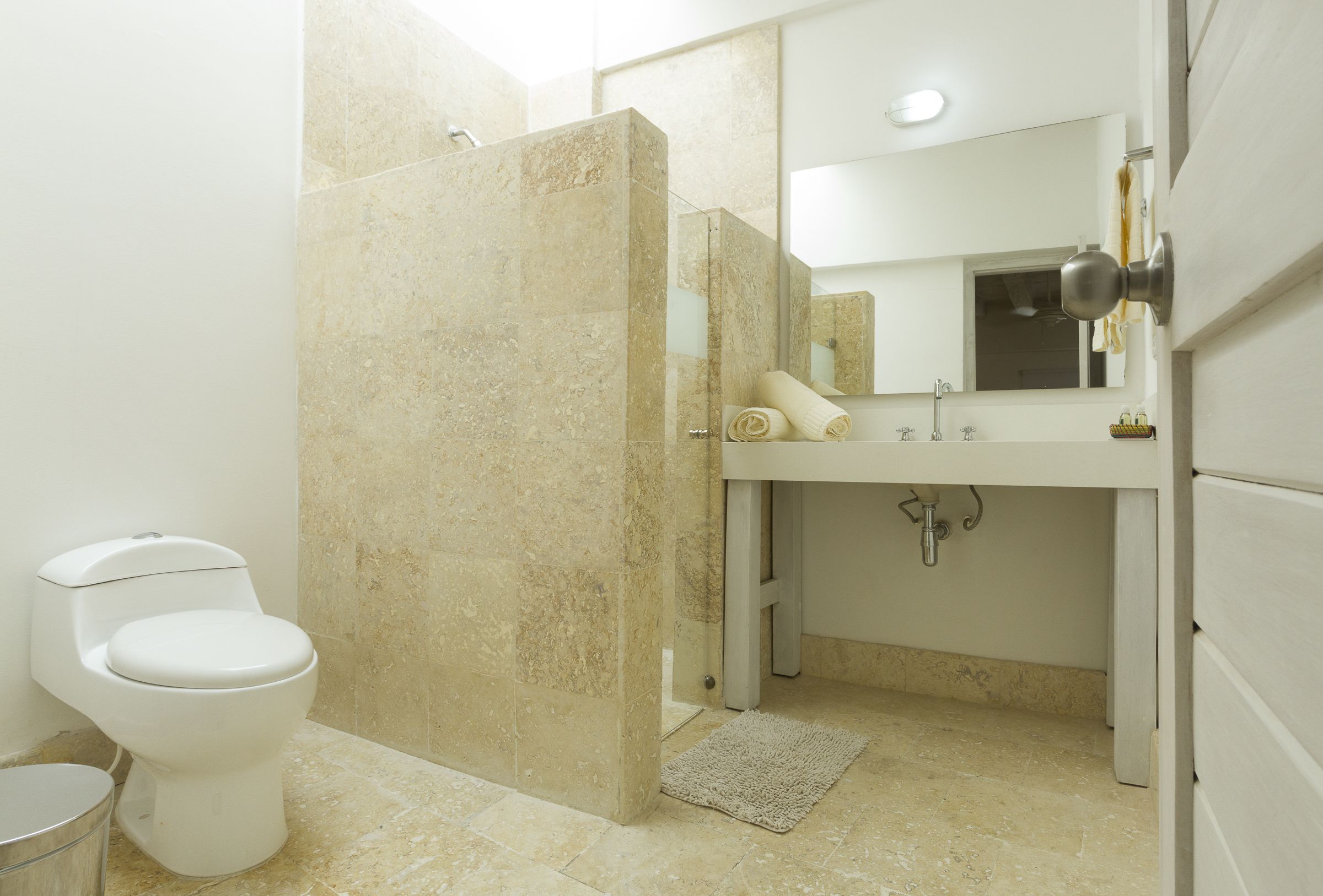 Un baño con inodoro, lavamanos, espejo y zona de ducha.