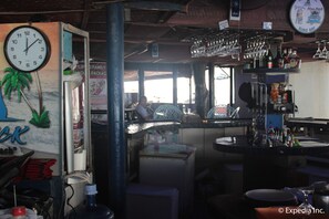 A bar area with a clock, shelves with bottles, and a counter. - Blue Rock Beach Resort (Olongapo)