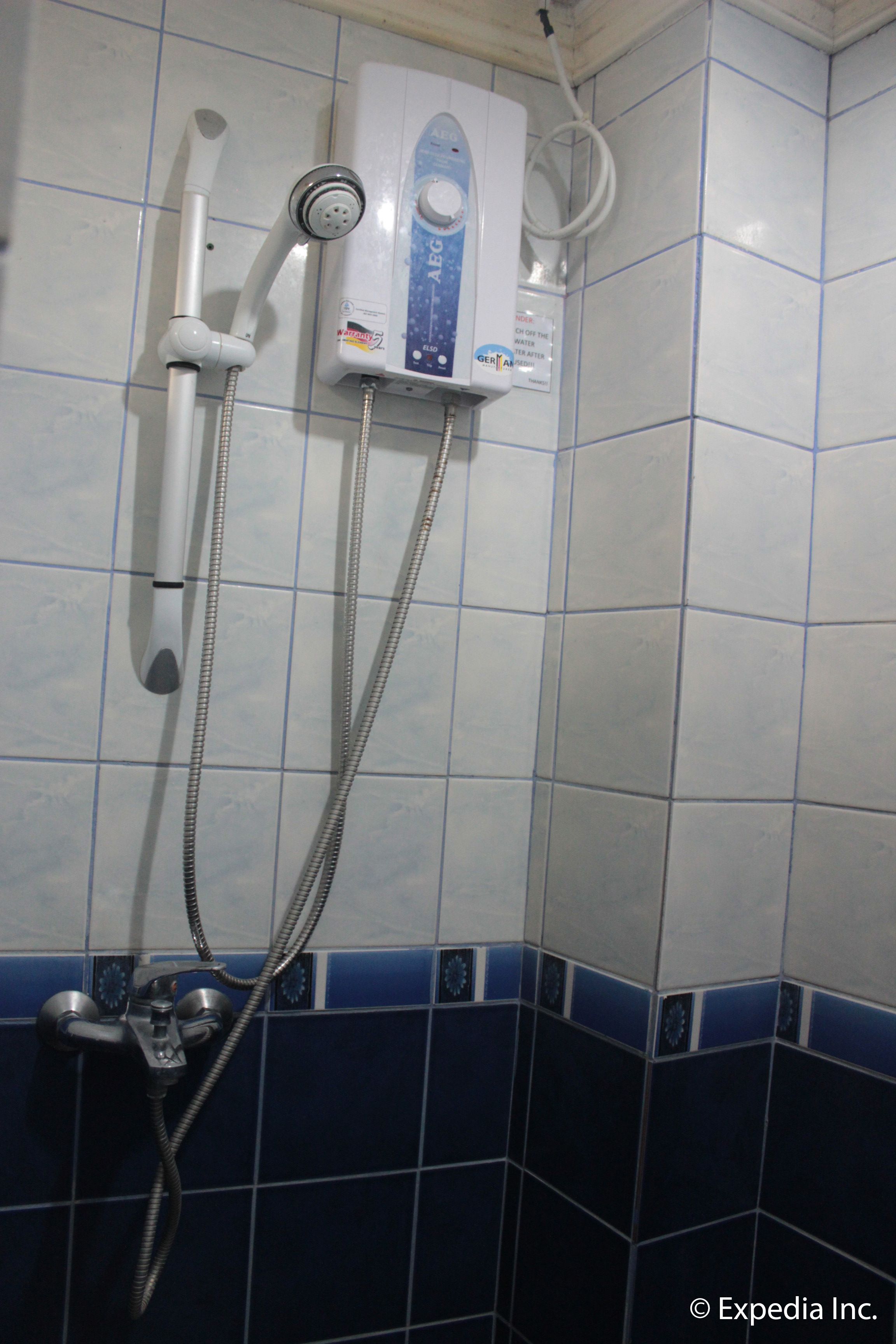 Un baño con sistema de ducha integrado, que incluye un cabezal de ducha manual y un panel de control en la pared.