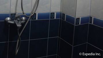 Un baño con sistema de ducha integrado, que incluye un cabezal de ducha manual y un panel de control en la pared.