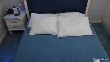 Een keurig opgemaakt bed met witte kussens en een blauwe spreidek in een hotelkamer.