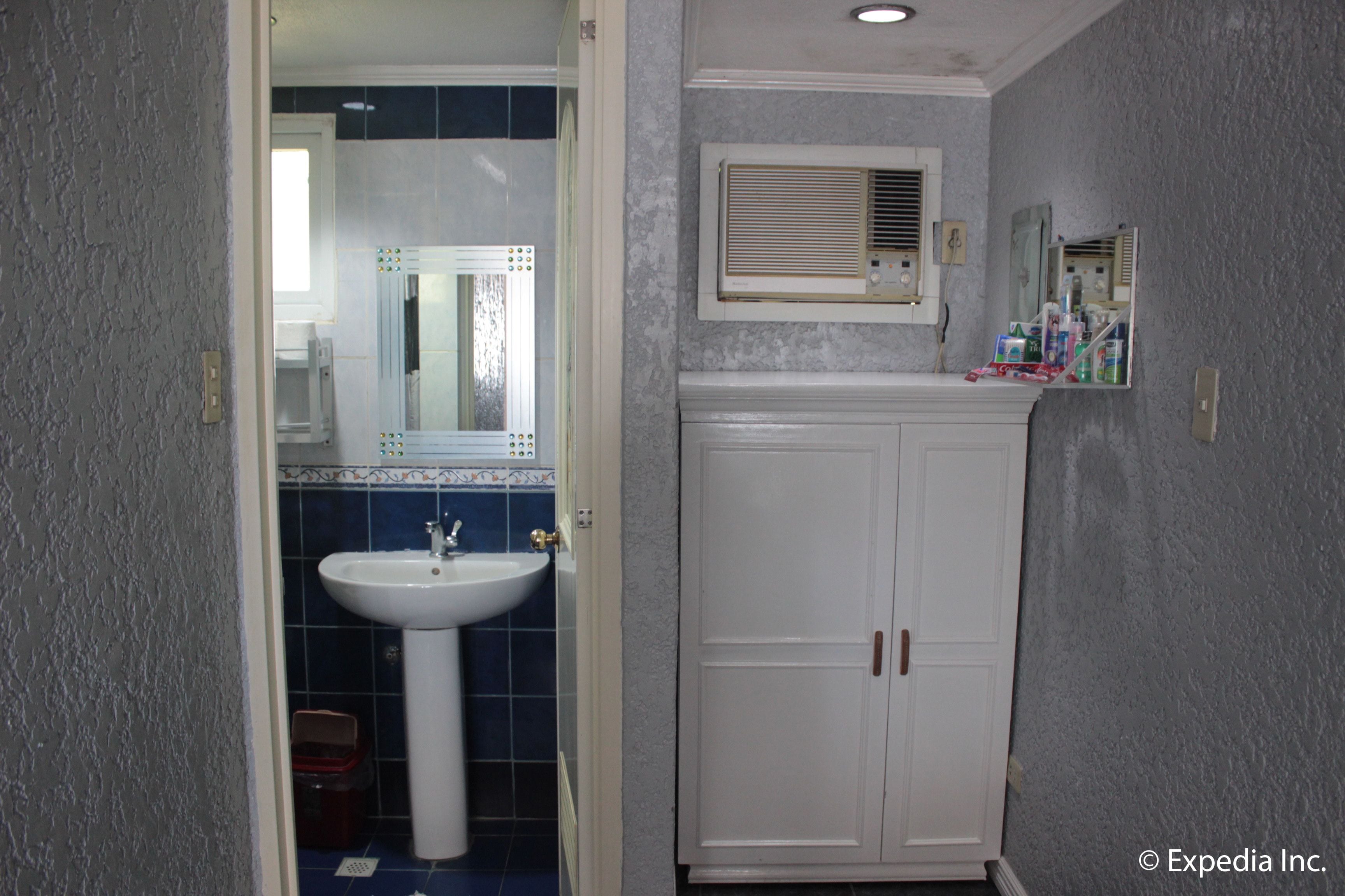 A bathroom with a white pedestal sink, a mirror above it, and a cabinet with a mirror above.
