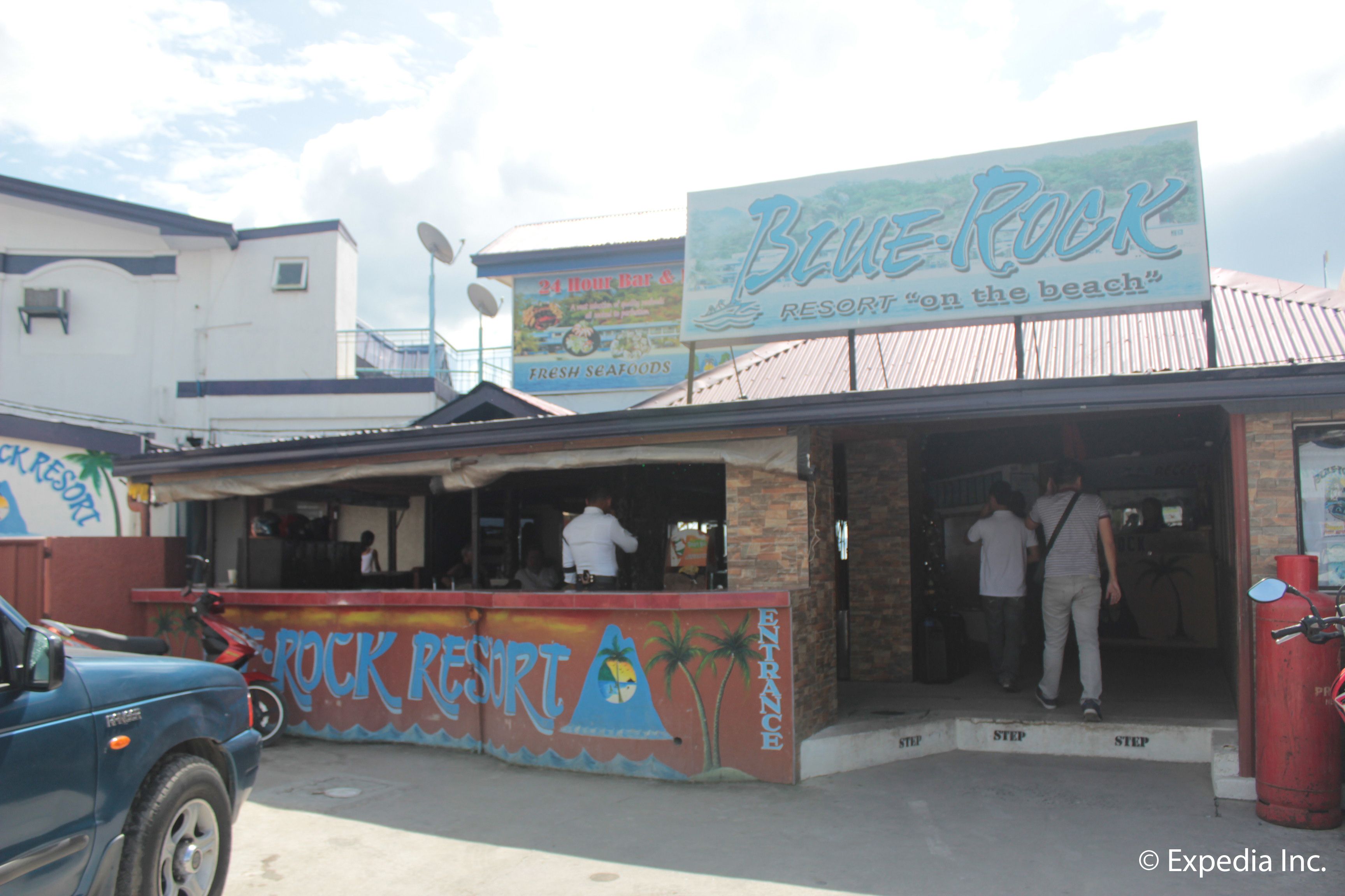 A Blue Rock Resort building with a beach sign, a 24-hour bar, and fresh seafood offerings.