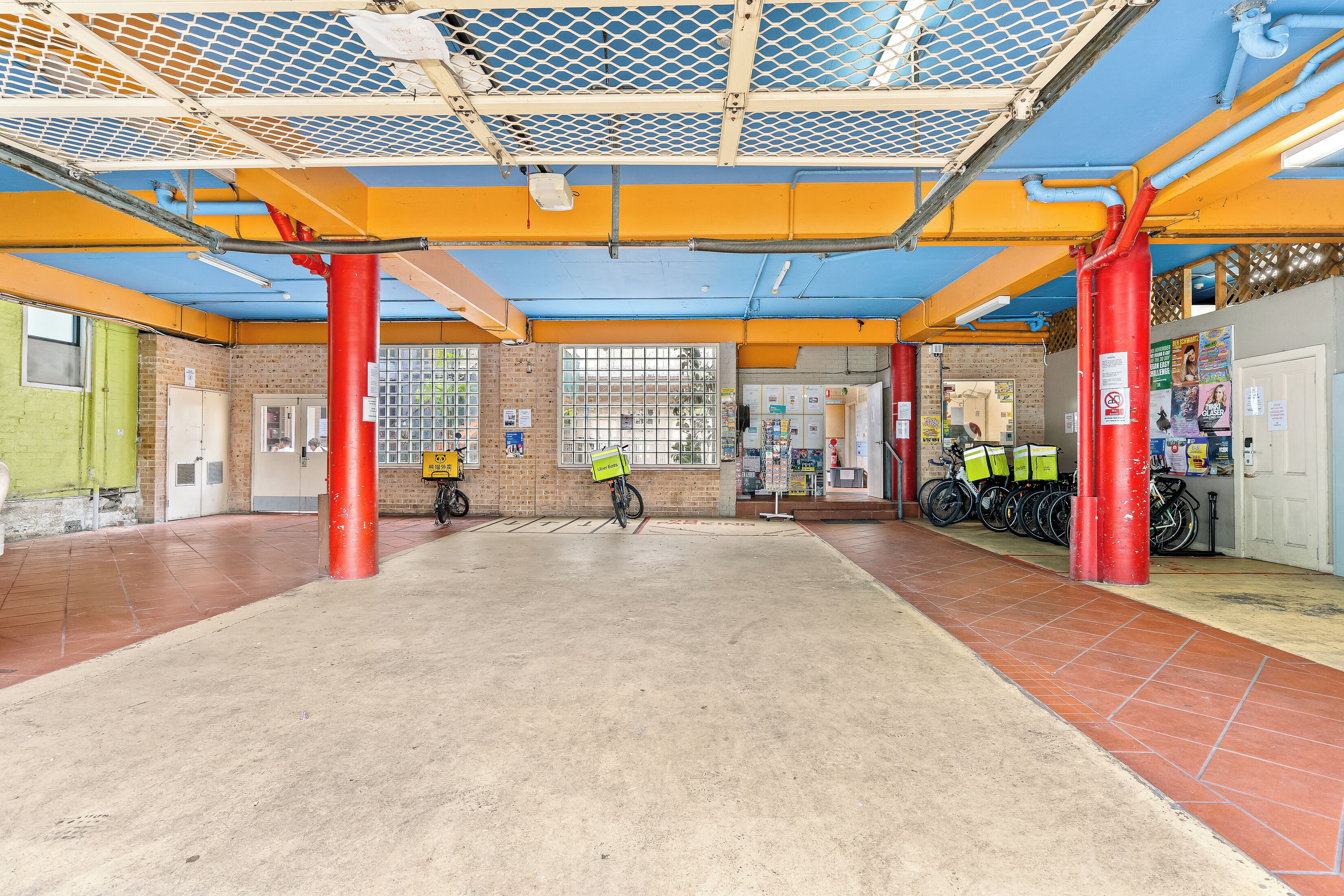 A spacious indoor area with a high ceiling, red pillars, and a tiled floor.
