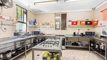 A commercial kitchen with stainless steel appliances, storage shelves, and a tiled floor.