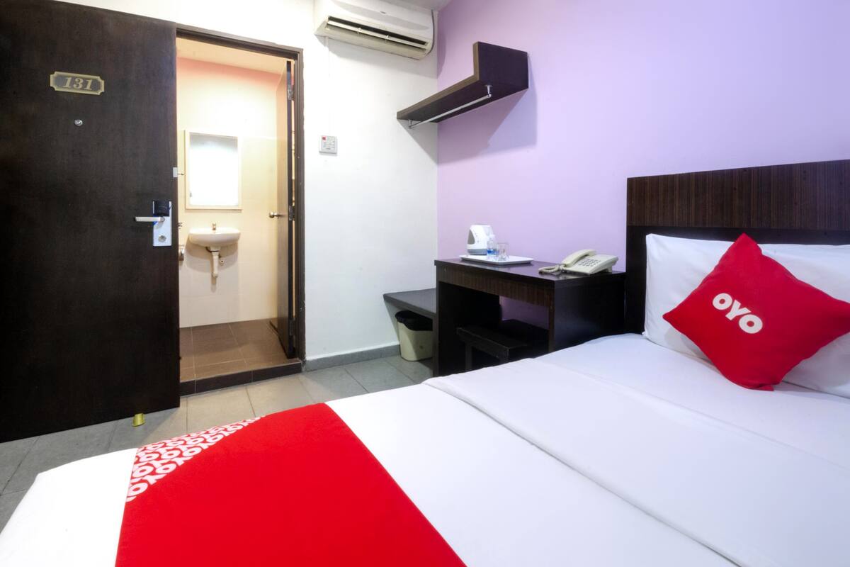 Une chambre d’hôtel équipée d’un lit, d’un bureau, d’un téléphone, d’un lavabo et d’un appareil de climatisation.