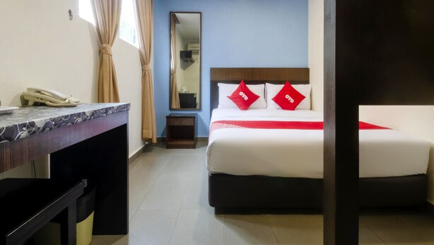 Une chambre d’hôtel avec un lit, un bureau, un téléphone et un miroir.