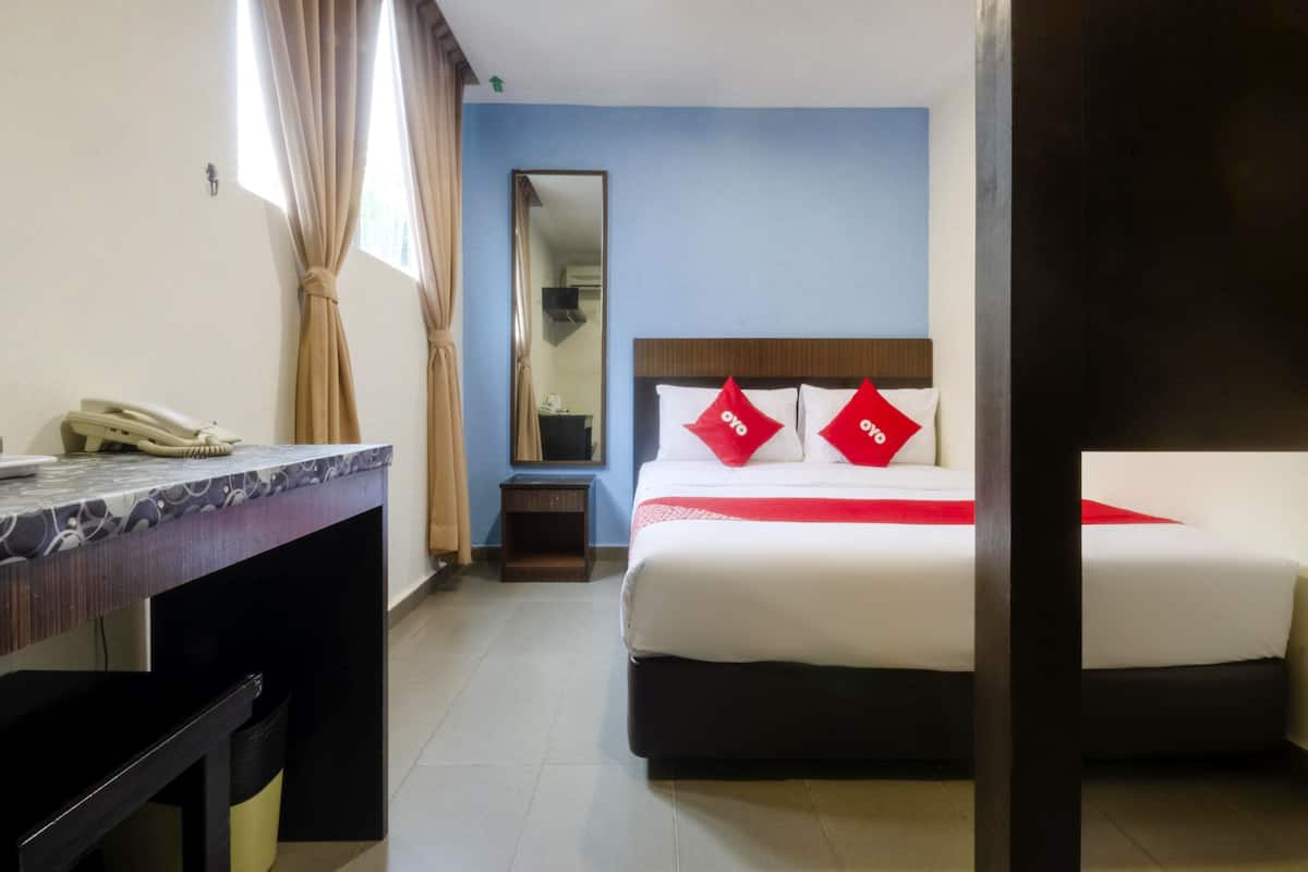 Une chambre d’hôtel avec un lit, un bureau, un téléphone et un miroir.