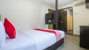 Une chambre d’hôtel avec un lit, un téléviseur fixé au mur et une porte donnant sur une autre pièce.