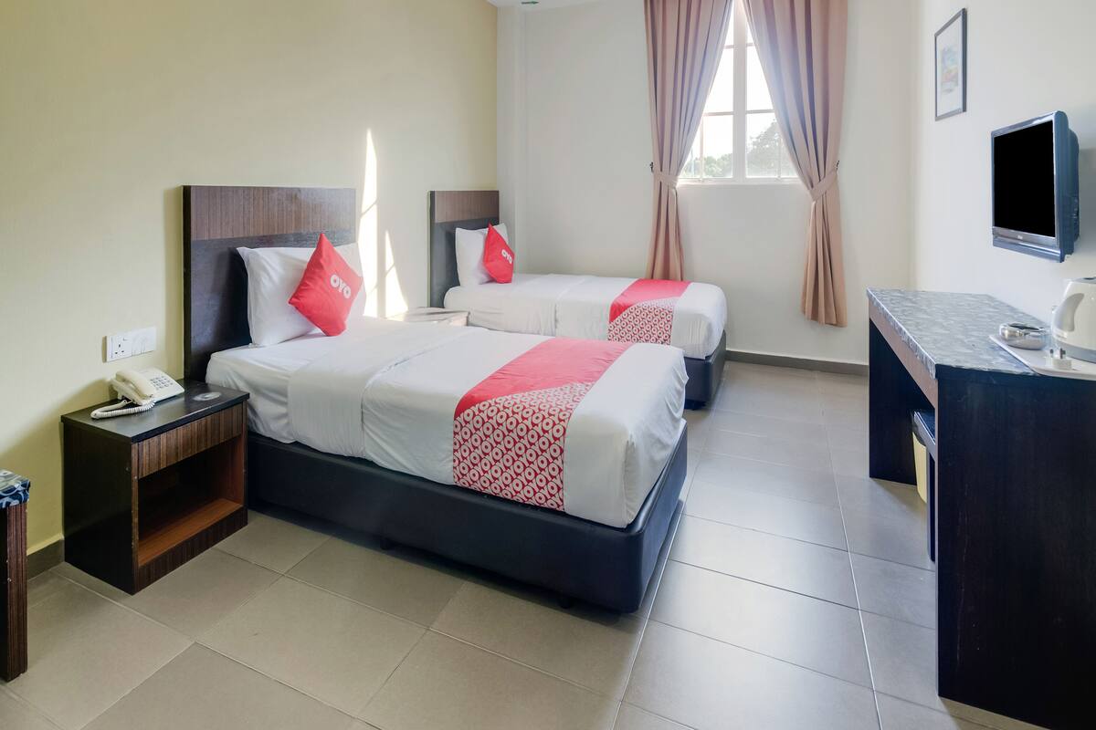 Une chambre d’hôtel avec deux lits, un bureau, un téléphone et une télévision.