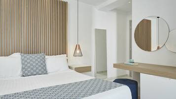 Habitación de hotel moderna con una cama grande, una mesita de noche, un escritorio, un espejo y una lámpara colgante.