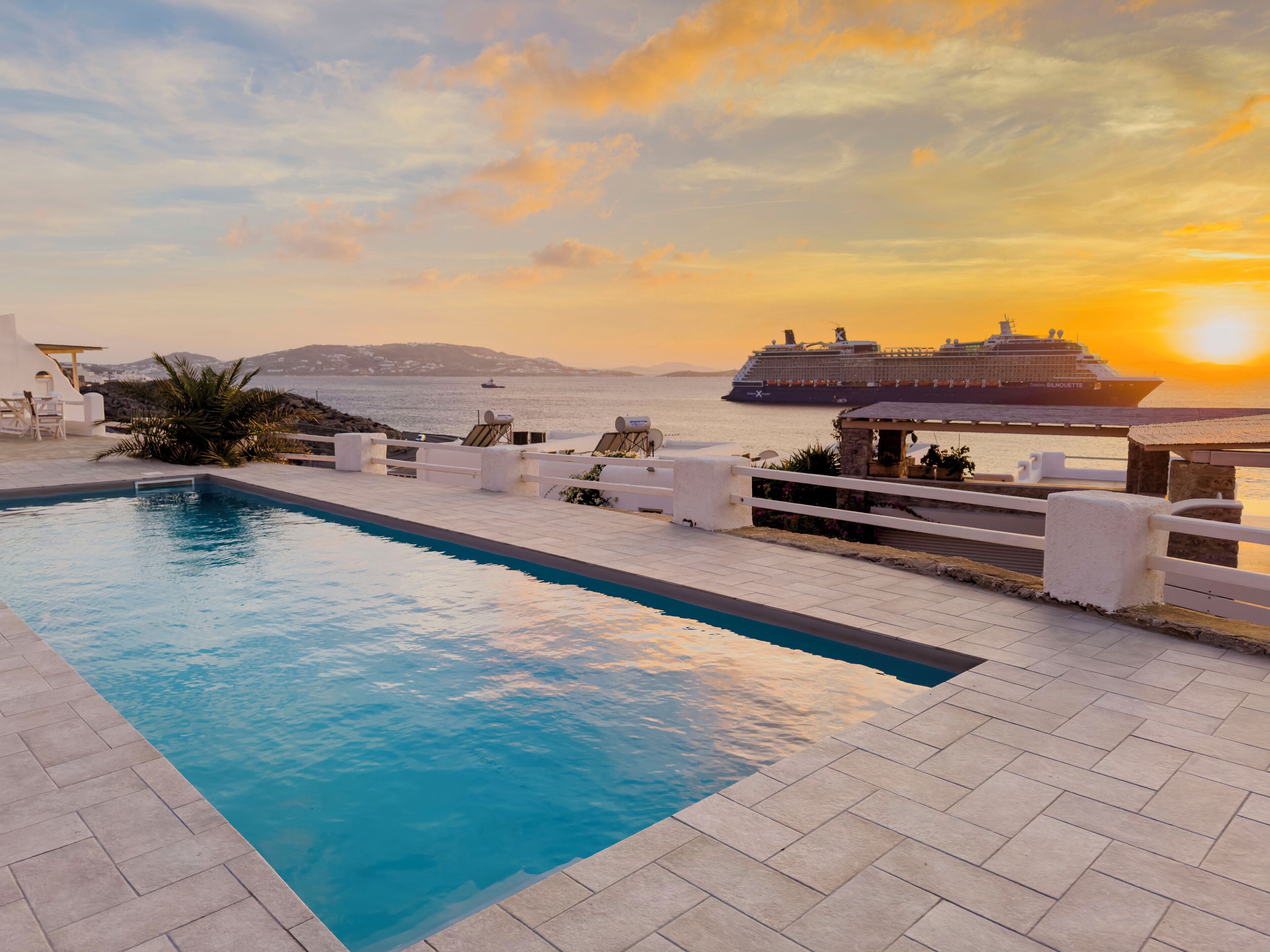 Ein Schwimmbecken mit Meerblick und einem Kreuzfahrtschiff im Hintergrund.