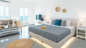 A modern bedroom with a large bed, a TV, and a view of the sea through the window. -  With-inn Mykonos Suites (Mykonos)