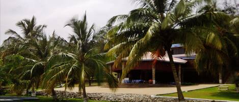Un resort tropical con palmeras, un muro de piedra y un edificio de techo rojo.