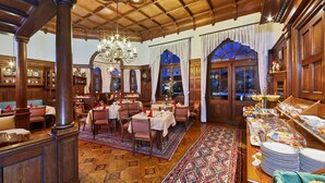 A dining area with wooden furniture, tables set for meals, and a buffet with various food items. - Hotel Aschenbrenner (Garmisch-Partenkirchen)