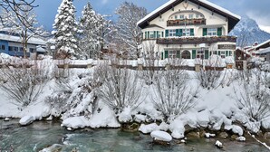 A hotel with a large balcony, a mountain backdrop, and a snow-covered landscape. - Hotel Aschenbrenner (Garmisch-Partenkirchen)