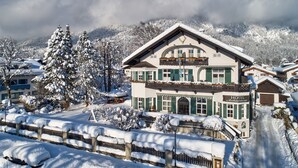 A hotel with a traditional Alpine architectural style, featuring a prominent balcony and a snow-covered landscape. - Hotel Aschenbrenner (Garmisch-Partenkirchen)