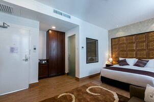 A hotel room with a bed, a wardrobe, a bathroom, and a wall-mounted artwork.