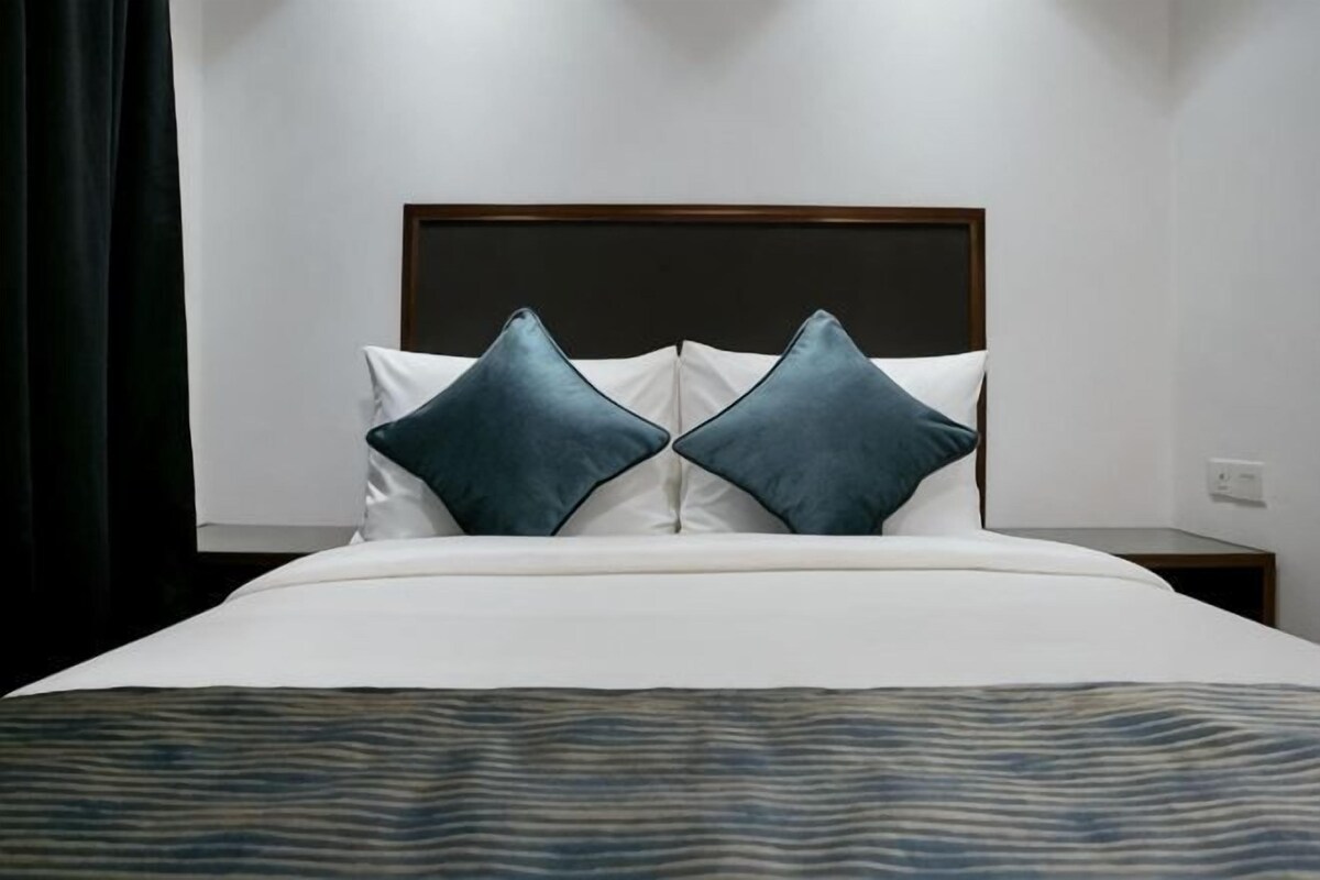 A neatly made bed with a patterned bedspread, two pillows, and a wooden headboard.