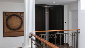A staircase with a wooden handrail and wrought iron balusters, leading to a dark door.