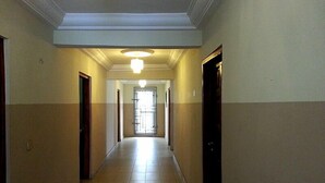 A long, narrow hallway with a tiled floor and a ceiling light fixture. - Kunta Kinte Hotel (Accra)