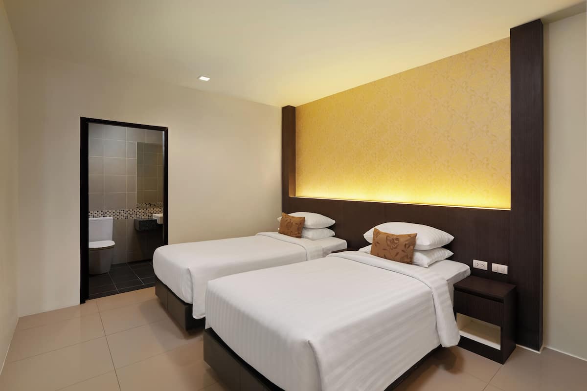 A hotel room with two beds, a bathroom, and a large wall-mounted light fixture.