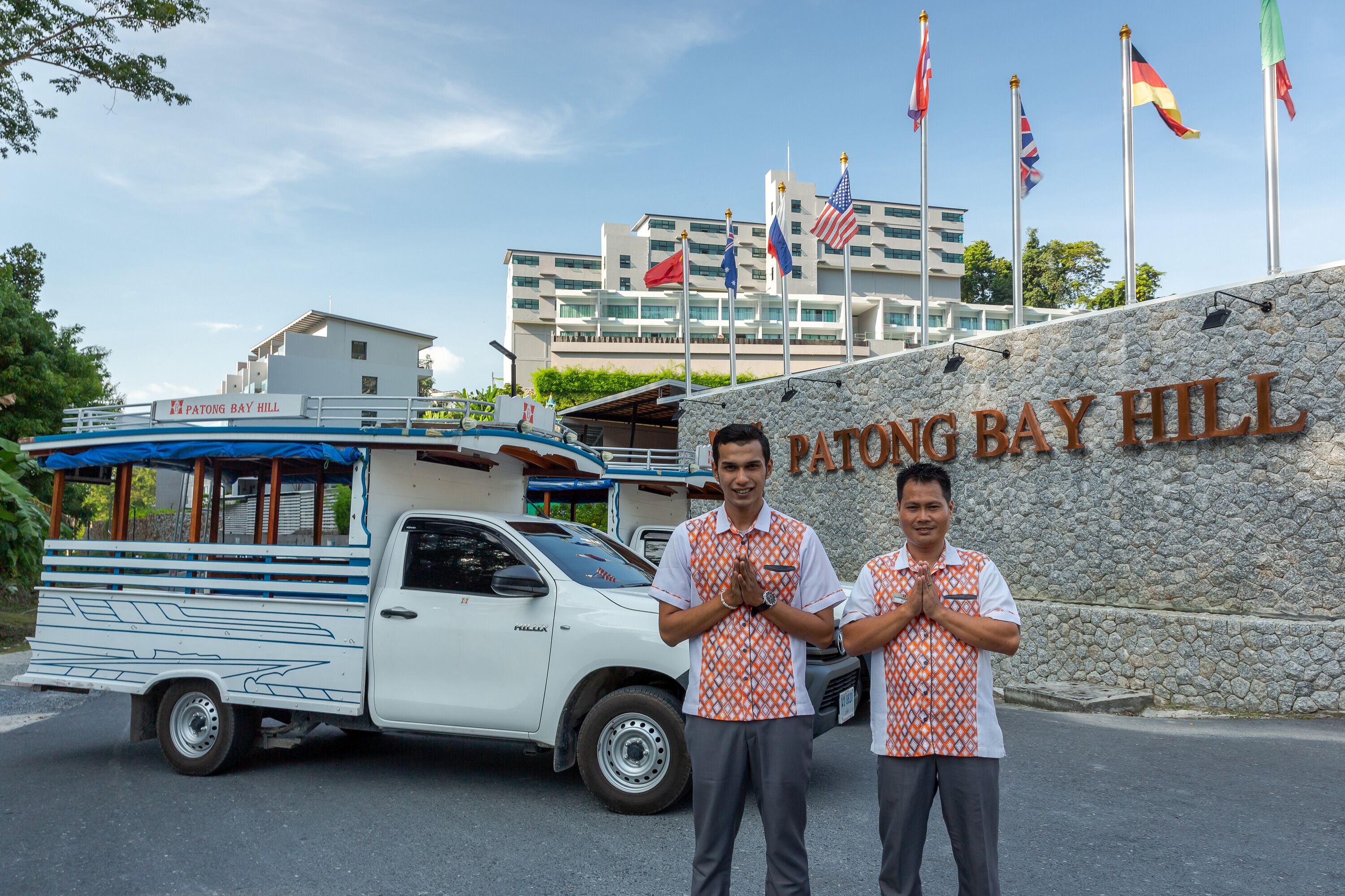 Ein Gebäude mit einem Schild, auf dem „Patong Bay Hill“ steht, und mehreren Flaggen.