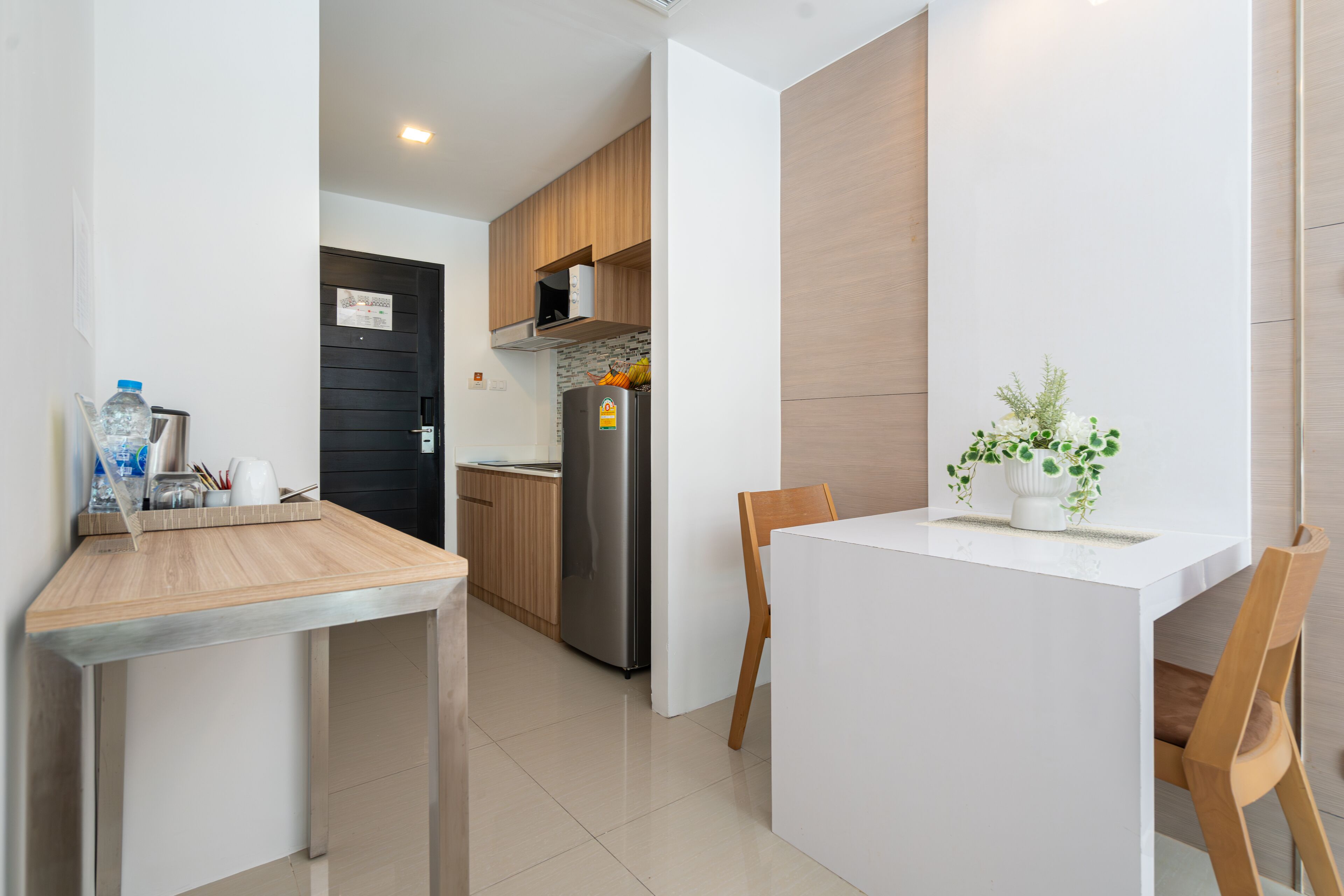 Een moderne keuken met een houten aanrecht, roestvrijstalen apparatuur en een eethoek met een witte tafel en stoelen.