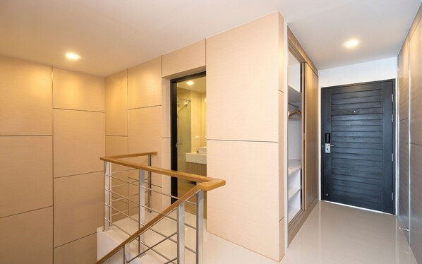 A modern interior with a staircase, a dark door, and a bathroom visible through an open door.