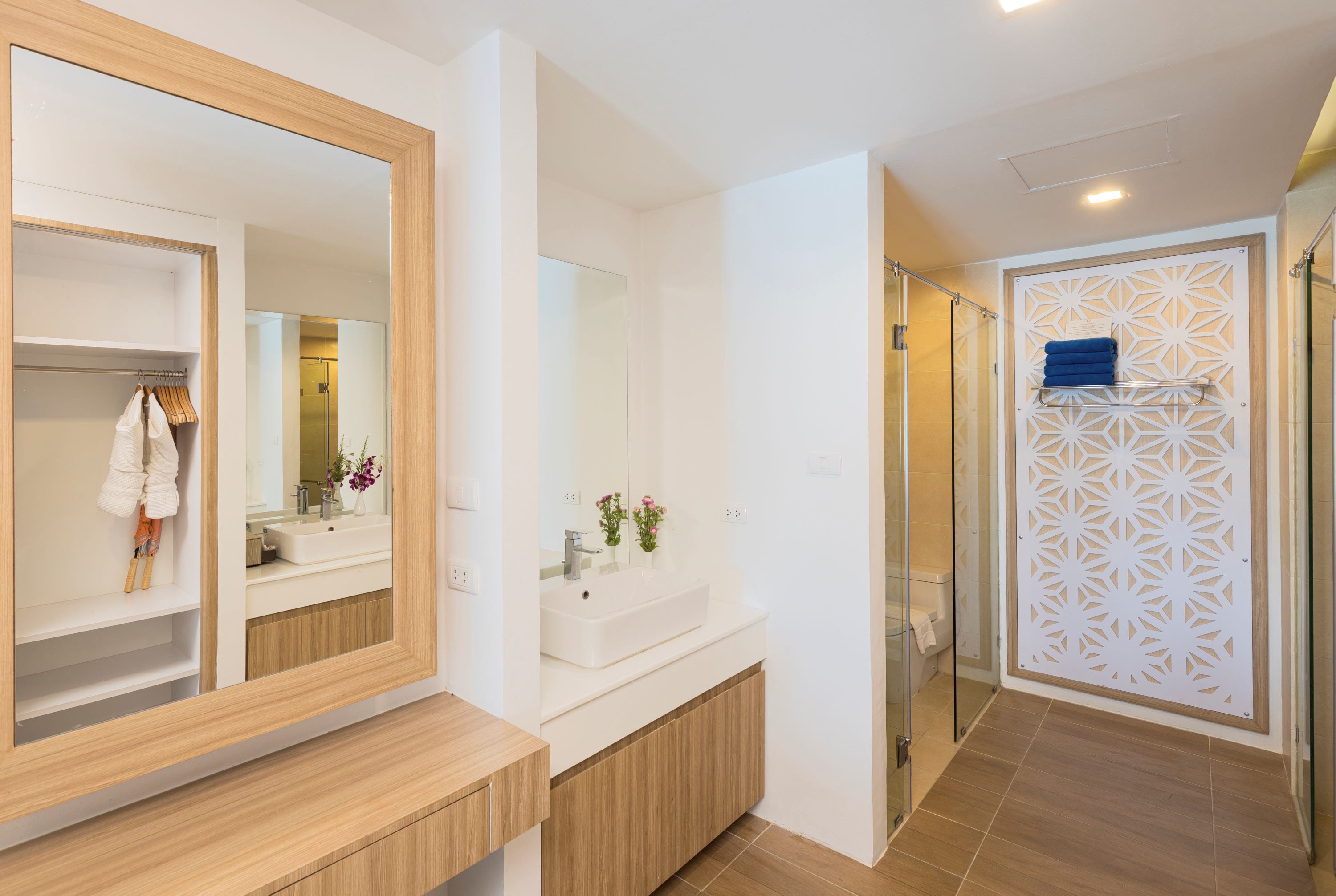 Un baño moderno con un espejo grande, un lavamanos blanco y una zona de ducha.