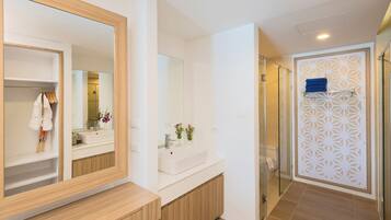 Un baño moderno con un espejo grande, un lavamanos blanco y una zona de ducha.