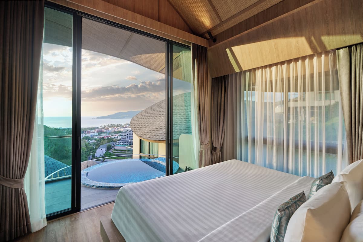 A bedroom with a large bed, a view of a swimming pool, and a balcony with a glass door.