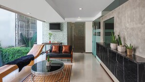 Un interior moderno con una mesa de vidrio, sofá de cuero negro y vistas al exterior.