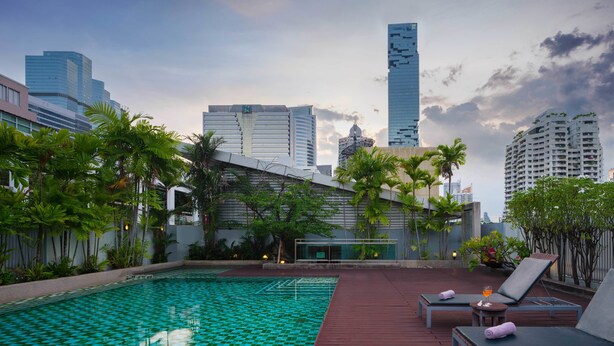 A rooftop pool with a checkered tile pattern, surrounded by lounge chairs and potted plants. - Silom Lofts Hotel (Bangkok)