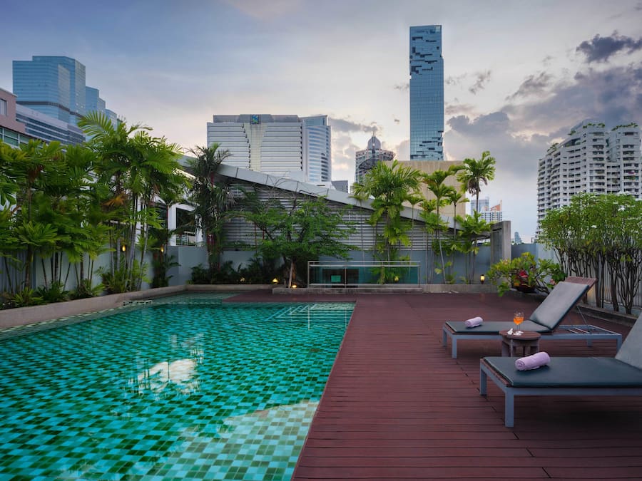 Una piscina al aire libre, sillones reclinables de piscina