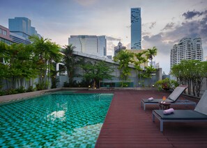 A rooftop pool with a checkered tile pattern, surrounded by lounge chairs and potted plants. - Silom Lofts Hotel (Bangkok)