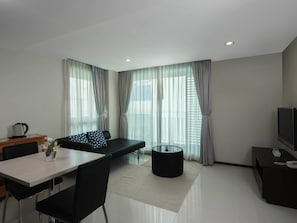 A modern living room with a sofa, dining table, and TV.