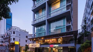A multi-story hotel with balconies, a coffee shop on the ground floor, and a parking area. - Silom Lofts Hotel (Bangkok)