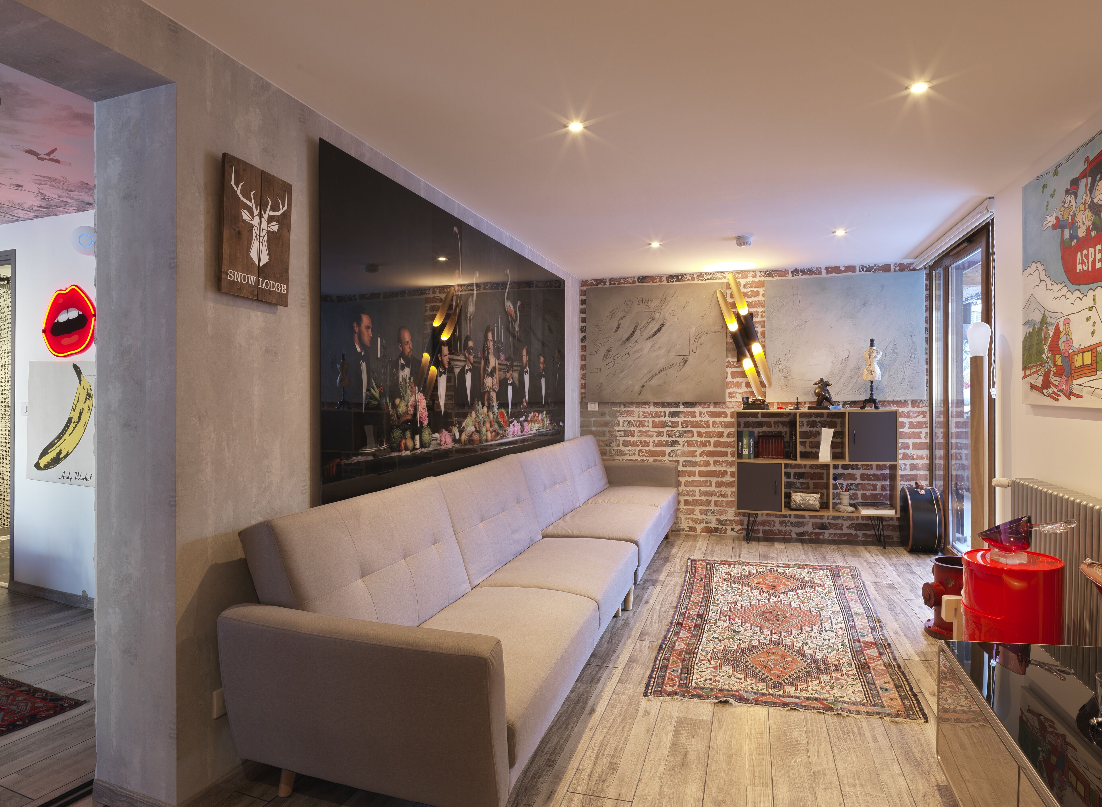 A modern living room with a sofa, a large painting, a fireplace, and a brick wall.