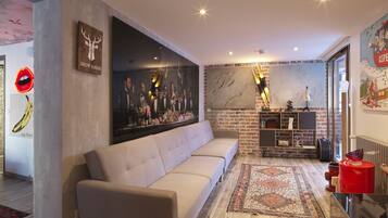 A modern living room with a sofa, a large painting, a fireplace, and a brick wall.