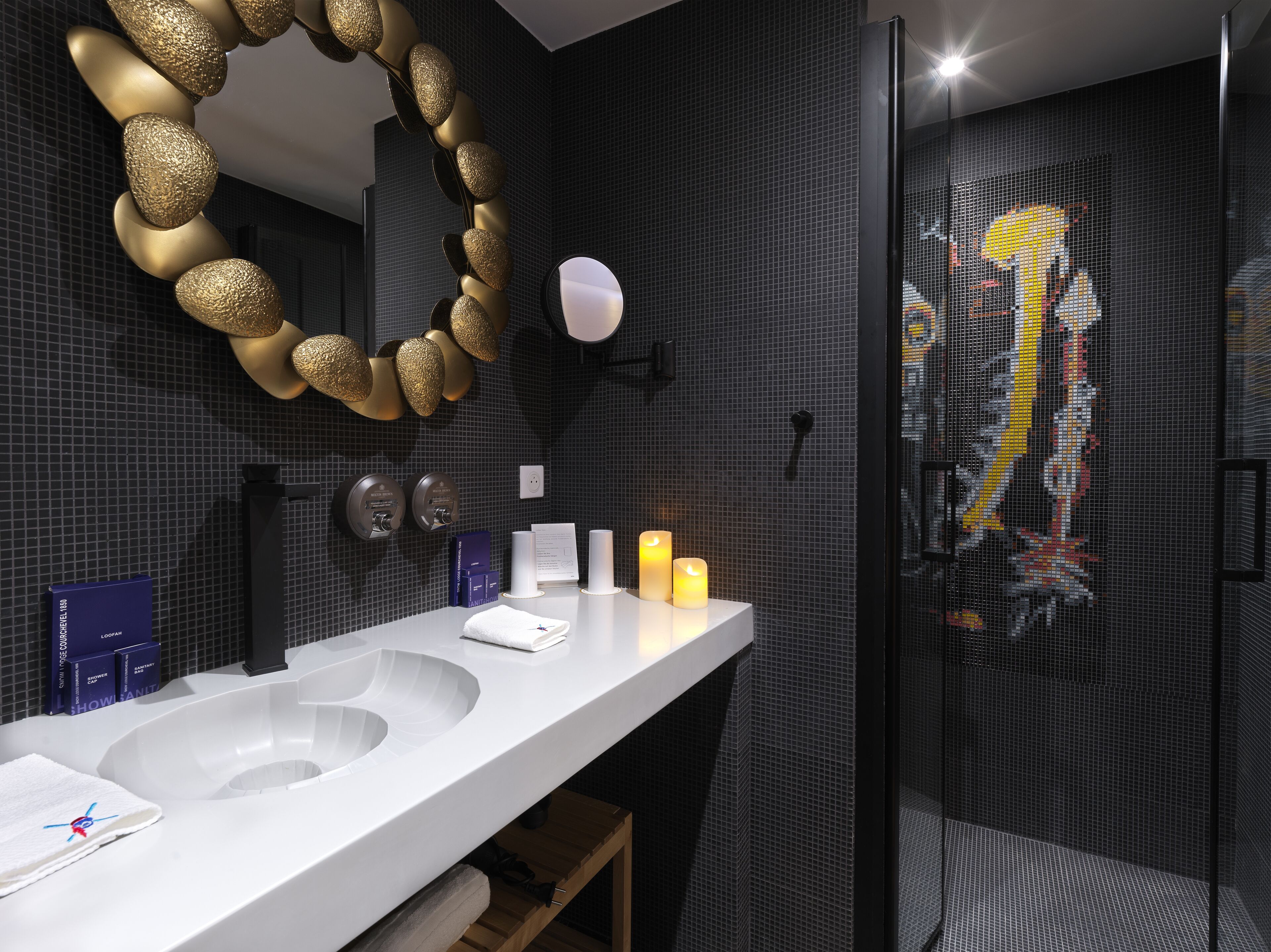 Un baño moderno con un lavabo blanco, un espejo decorativo dorado y una zona de ducha.