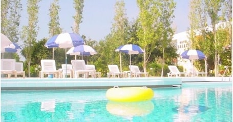 Una piscina al aire libre, sombrillas, sillones reclinables de piscina