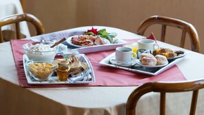 A breakfast table with a tray of pastries, a bowl of cereal, a cup of coffee, and a glass of orange juice. - Galaxy Hotel (Kefalonia)