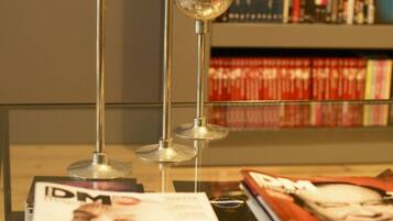 A table with books and magazines, a candle, and a metal lamp.