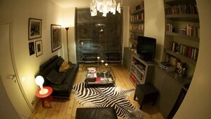 Una sala de estar acogedora con un sofá, una mesa de centro, alfombra de cebra y una estantería.