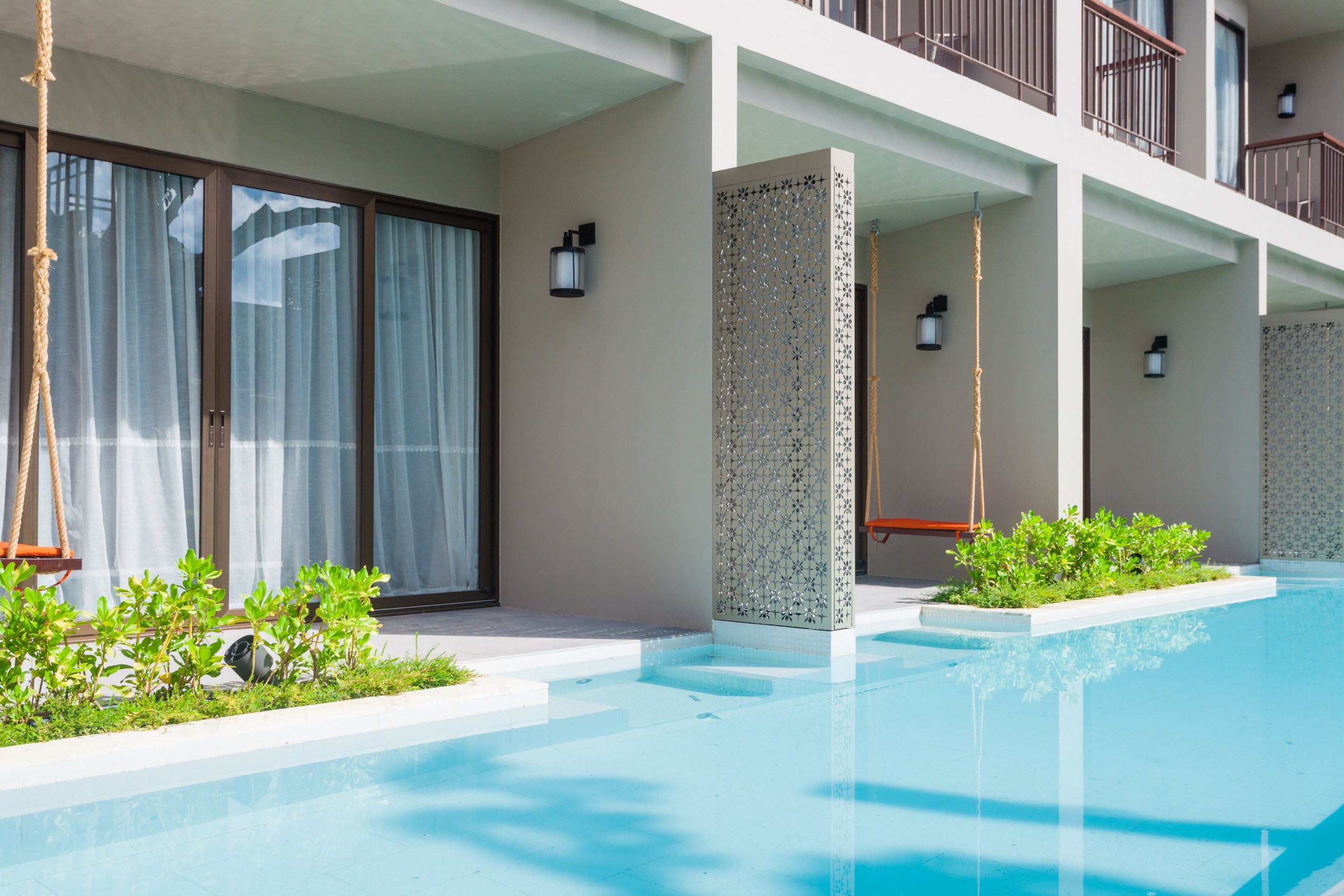 Um hotel moderno com piscina, janelas amplas e varanda com guarda-corpo.