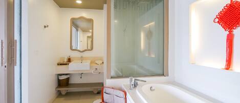 Une salle de bain moderne avec une grande baignoire, un lavabo avec un miroir au-dessus et un espace douche.