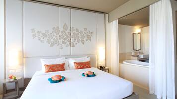Hotelkamer met een groot bed, twee kussens, een nachtkastje, een badkamer met wastafel en spiegel, en een gordijn.