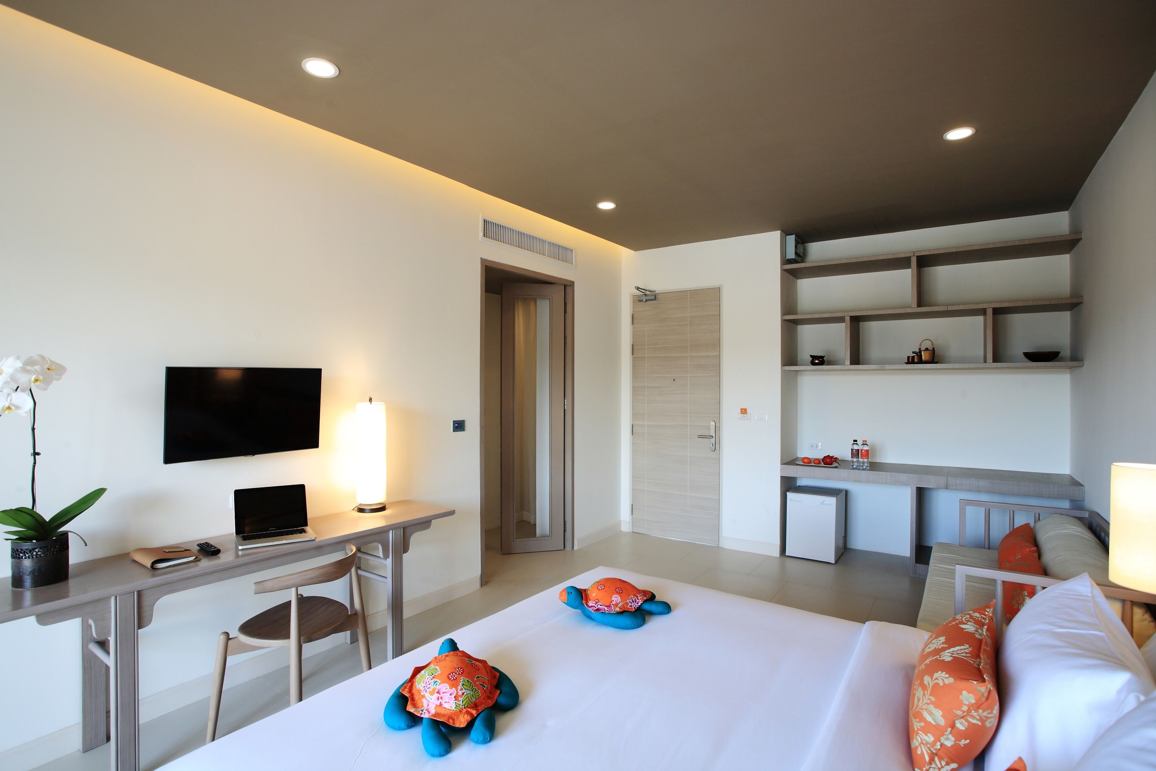 Een hotelkamer met een bed, bureau en een klein kitchenette.