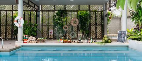 A pool area with a tiled deck, a lifebuoy, and various items like bottles and fruits.